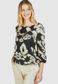 Schwarze Bluse mit beigem abstractem Muster, runder Ausschnitt, dreiviertel Ärmel, leichtes Material und leicht lockere Passform.