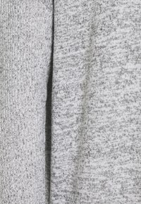 Tessuto grigio lavorato a maglia con una combinazione di tonalità chiare e scure, caratterizzato da un motivo testurizzato. Il materiale appare morbido e leggermente elasticizzato.