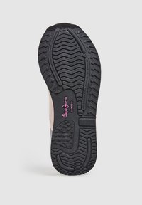 Suela de goma negra con patrones de agarre texturizados, con un logo rosa. La entresuela es de color gris, con una sección superior suave en tonos más claros.
