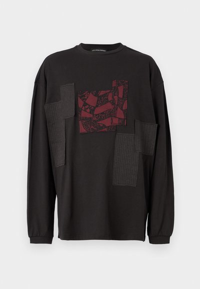 Chemise noire à manches longues avec un patch texturé bordeaux orné de motifs abstraits et des accents en tissu côtelé à l'avant. Encolure ronde.