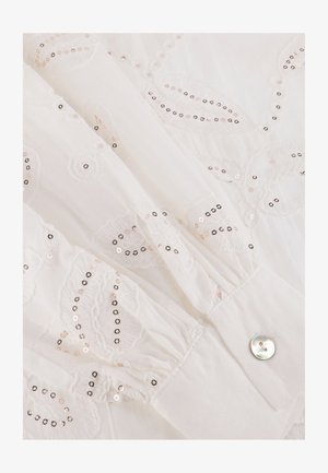 Witte stof met geborduurde bloemenpatronen. Voorzien van pailletten in roségoud en zwart. Manchetknopen hebben een geplooide textuur en een glanzend knopdetail.