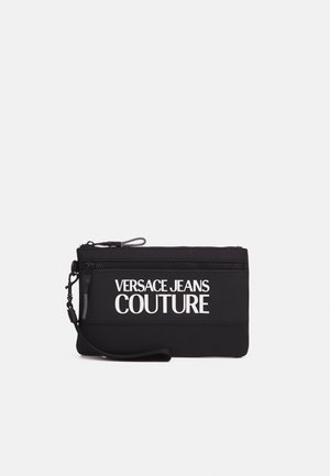 Czarna prostokątna saszetka na nadgarstek z dwoma zamykanymi na zamek komorami i białym logo "Versace Jeans Couture" z przodu.