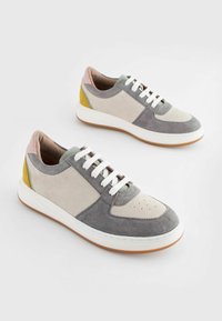 Niedrig geschnittene Sneakers mit einer Mischung aus grauem, beigem, pastellfarbenem und gelbem Wildleder, weißen Schnürsenkeln, einer strukturierten Gummisohle und einem perforierten Zehenbereich.
