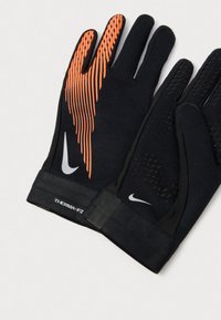 Egy pár fekete Nike Therma-FIT kesztyű narancssárga csíkozással az egyik kesztyűn, és kis fehér Nike pipa logók mindkét csuklón.
