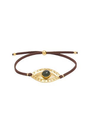 Regulowana brązowa bransoletka sznurkowa ze złotym zawieszką w kształcie oka z centralnym zielonym kamieniem i małymi złotymi ćwiekami wokół krawędzi.