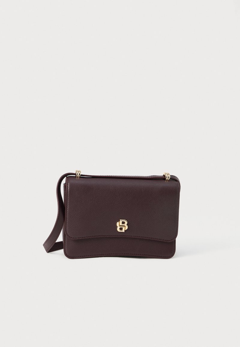 Burgundijas krāsas ādas crossbody soma ar gludu tekstūru, zelta detaļām, ar vāciņa aizdari un izspiestu logotipu uz priekšpuses.