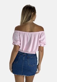 Rosa schulterfreie Bluse mit elastischen Bündchen und Saum, kombiniert mit einem taillierten Denim-Minirock mit fransigem Saum und Gesäßtaschen.