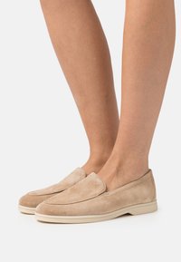 Beiga mockasiner i mocka med rund tå och elastisk slip-on-design. Ljust gummisul med slät finish och minimal sömnadsdetalj.