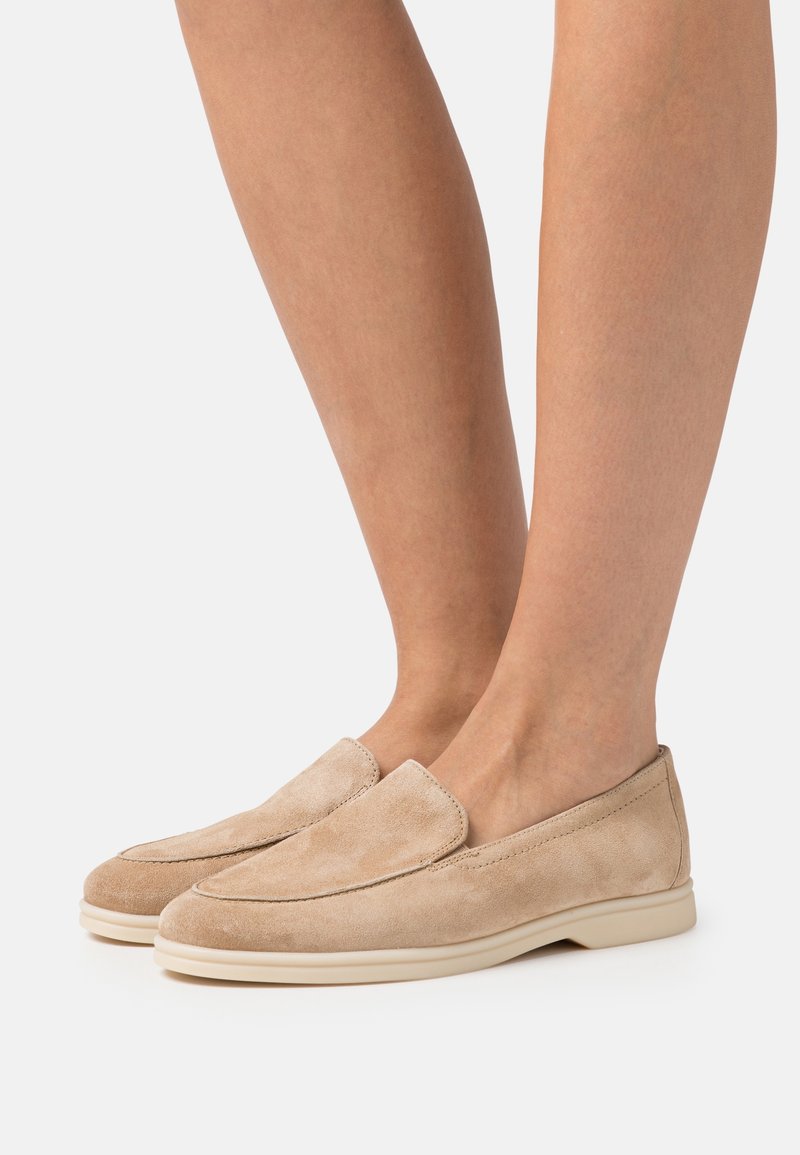 Beiga mockasiner i mocka med rund tå och elastisk slip-on-design. Ljust gummisul med slät finish och minimal sömnadsdetalj.