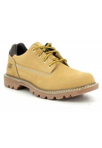 Zapato de cuero marrón con cordones amarillos, suela robusta y acentos en el talón negros. Presenta detalles de costura y un logo en el lateral.