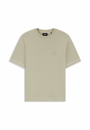 T-shirt beige clair à manches courtes avec col rond, texture subtile, petit logo brodé "SD" sur la poitrine et double rayures blanches sur les manches.