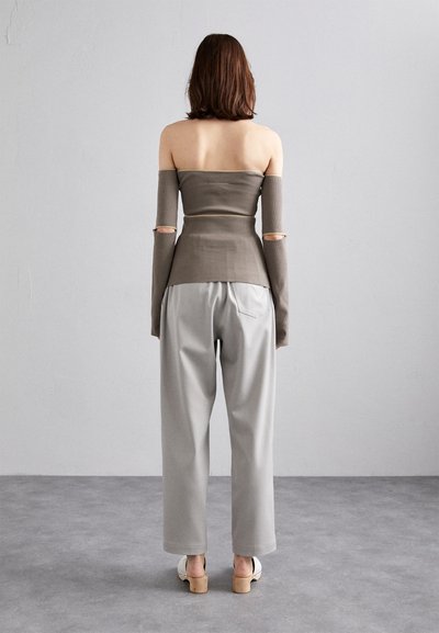 Grå ribbet off-shoulder topp med lange ermer og utskjæringer, sammen med løstsittende grå bukser og lyse hæler.
