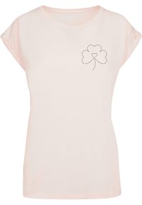Lyserød T-shirt lavet af blød bomuld, med rullede korte ærmer og en sort omrids af en kløver med et hjerte i midten.