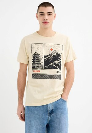 Camiseta de manga corta beige con estampados gráficos en negro de una pagoda y el Monte Fuji, con acentos de sol rojo y un borde con patrón de olas.