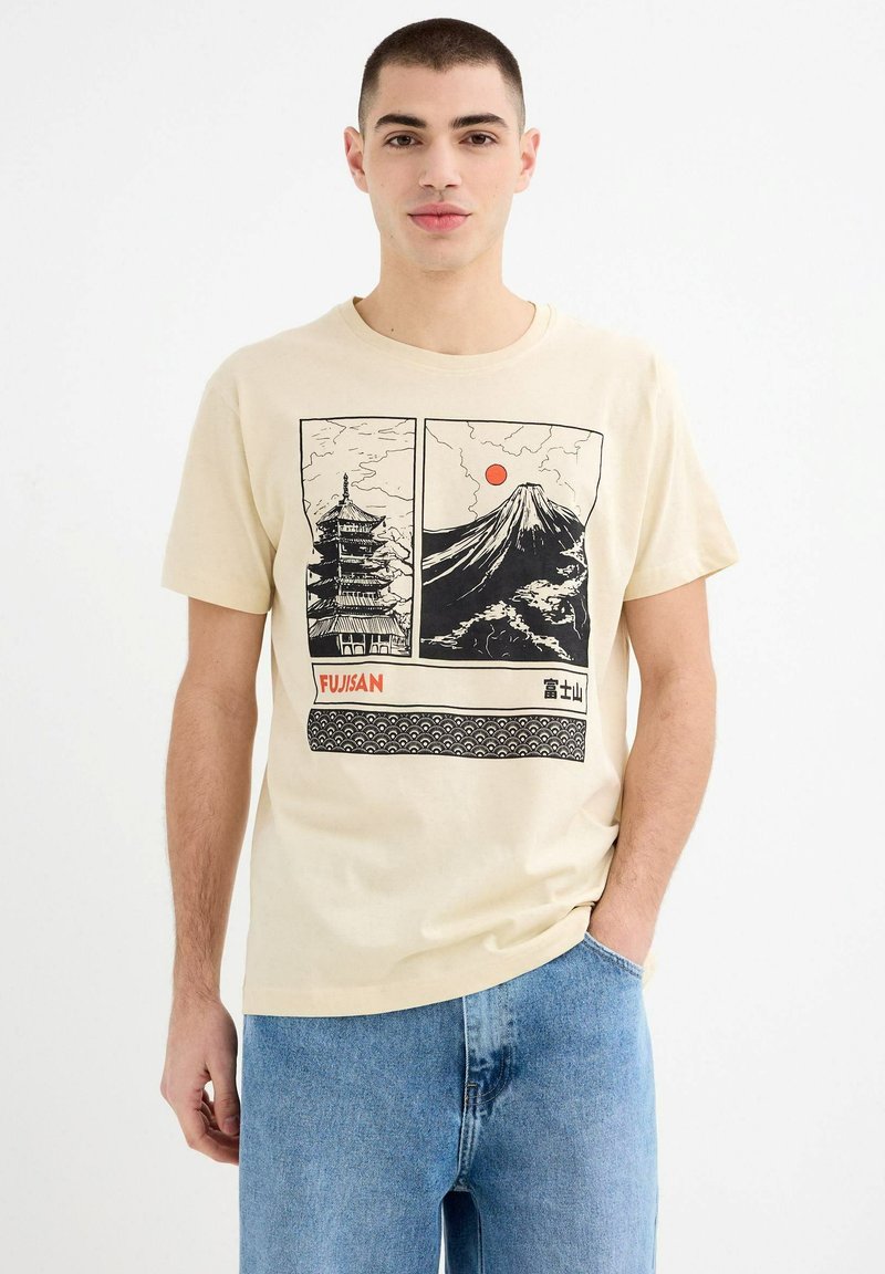 Camiseta de manga corta beige con estampados gráficos en negro de una pagoda y el Monte Fuji, con acentos de sol rojo y un borde con patrón de olas.