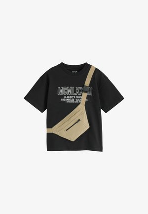 T-shirt noir à manches courtes avec chiffres romains blancs et texte de coordonnées, associé à une pochette bandoulière beige zippée.