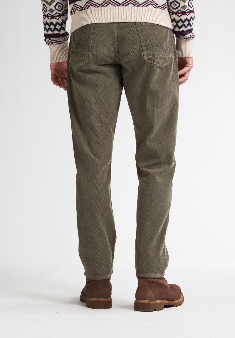 Pantalones de pana en verde oliva con corte recto, que cuentan con bolsillos traseros y se combinan con botas de tobillo marrones. Superficie texturizada visible.