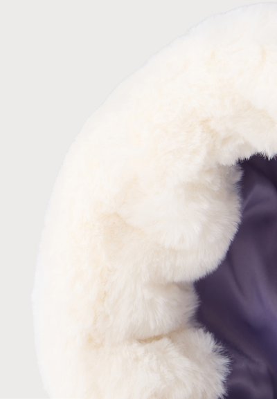 Gros plan sur un tissu doux en fausse fourrure blanche entourant une doublure satinée lisse violet foncé.