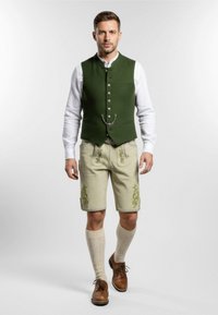 Traditionelt tøj med en grøn vest, hvid skjorte, beige shorts med blomsterbroderi, knælange strikkede sokker og brune sko.