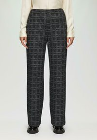Zwart en grijs geblokte broek met een rechte pijpdesign, textuurstof en een elastische tailleband, gecombineerd met glanzend zwarte schoenen.
