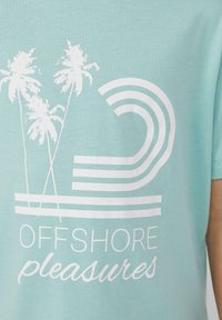 Hellblaues Baumwoll-T-Shirt mit weißem Grafikdesign von zwei Palmen und gewellten Linien, Text "OFFSHORE pleasures", Rundhalsausschnitt, kurze Ärmel.
