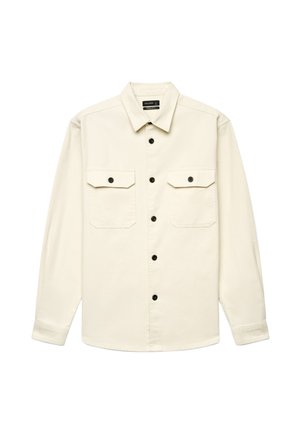 Camicia beige a maniche lunghe con bottoni neri sul davanti e su due tasche sul petto, mostrata distesa senza sfondo.