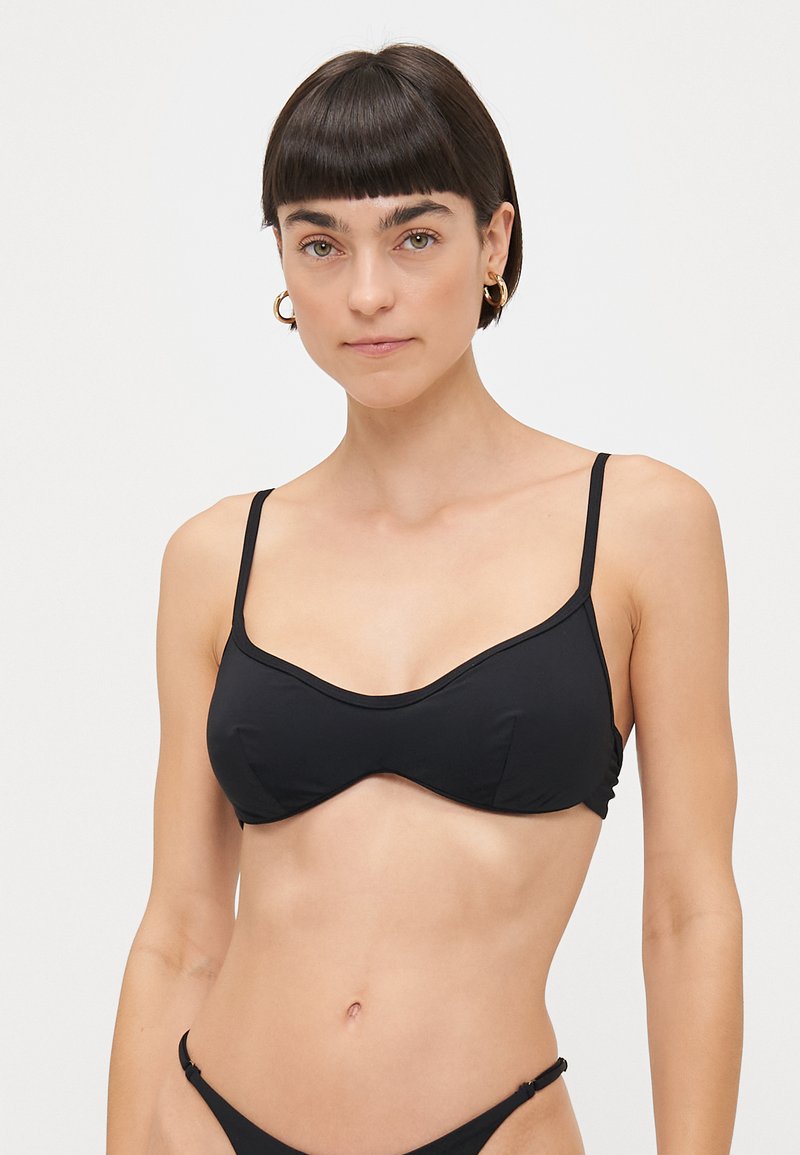 Top bikini nero con spalline sottili regolabili, design con sottoseno strutturato e texture in tessuto liscia. Nessun motivo o accento visibile.