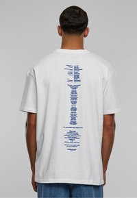 Hvid bomuld t-shirt med et vertikalt blåt tekstdesign på ryggen, med en afslappet pasform og korte ærmer.