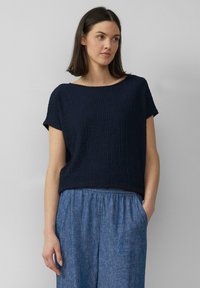 Toppik lyseblå denim bukser med løs passform, kombinert med en navy teksturert kortermet topp med vid hals.