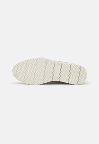 Rubber shoe sole featuring a zigzag tread pattern, predominantly white, with a smooth texture and embossed size detail.
