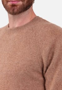 Brown knit sweater with a fitted neckline, soft texture, and raglan sleeves, featuring a smooth finish and no visible patterns or embellishments.