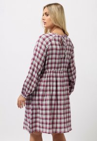 Pitkähihaisessa ruudullisessa mekossa on ryppyvyö, joka yhdistää vaaleanpunaisia ja valkoisia sävyjä. Takana on solmittava kiinnitys ja elastiset hihansuut. Kevyt kangas.