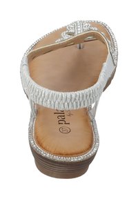 Sølv thong sandal med fletstribe, flad sål, dekoreret hardware og en brun tekstureret fodseng. Størrelsesmærket synligt indeni.