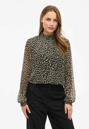 Blusa a stampa leopardata con colletto alto e arricciato e maniche lunghe e trasparenti, realizzata in materiale leggero; abbinata a pantaloni neri.