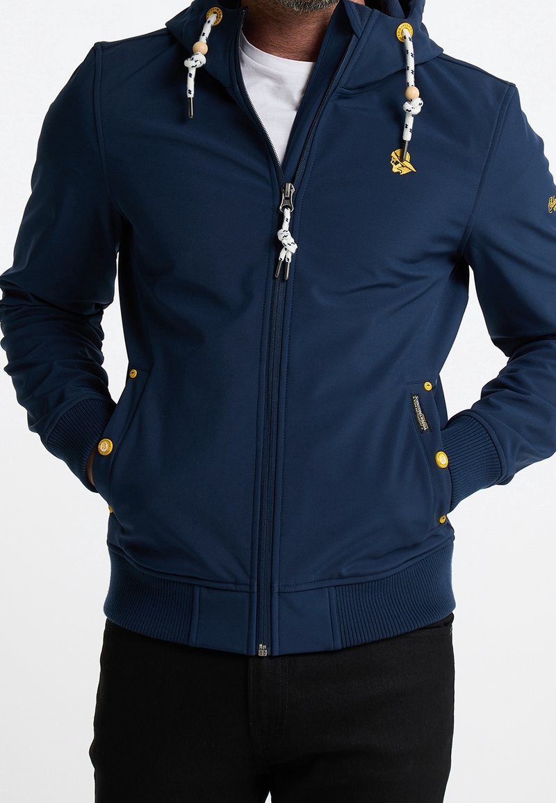 Marineblaue Zip-Hoodie aus weichem Stoff, mit weißen Kordeln mit Perlen, zwei Fronttaschen mit gelben Knöpfen und gerippten Bündchen.