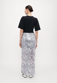 Sort t-skjorte i svart kombinert med en metallisk grå, lang paljettbelagt skjørt med et subtilt tie-dye mønster og ribbet tekstur.