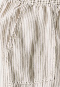 Beige en crèmekleurige gestreepte stof met een gladde textuur, voorzien van een geknoopt zakje en details van een geplooide taille.