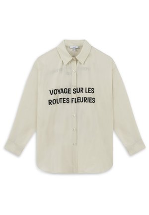 Crèmekleurig overhemd met knoopsluiting, voorzien van een puntkraag en lange mouwen, met zwarte tekst "VOYAGE SUR LES ROUTES FLEURIES" op de voorkant.