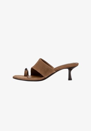 Braune Maultier-Sandale aus Wildleder mit einem niedrigen Kitten-Heel und einer Zehenlasche mit einem kleinen silbernen Detail, seitlich auf weißem Hintergrund gezeigt.