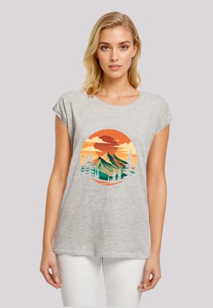 Graues T-Shirt mit kurzen Ärmeln, das ein kreisförmiges Grafikdesign von Bergen und Bäumen in Orange, Grün und Weiß vor einem Sonnenuntergangshintergrund zeigt.
