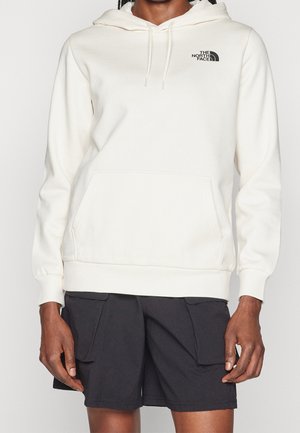 Person wearing a white The North Face hoodie with front pocket and drawstrings, paired with black cargo shorts.