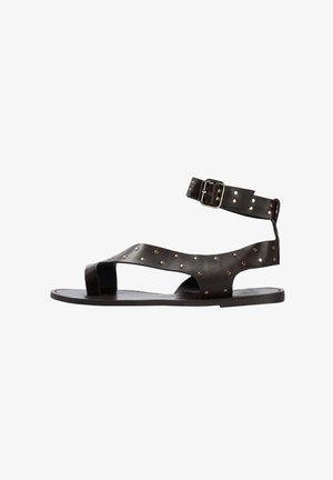 Sandales en cuir noir avec une bride de cheville, dotées de clous dorés sur le dessus et d'un design ouvert à l'avant. Semelle plate avec un minimum de rembourrage.