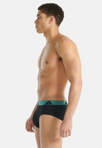 Czarne bokserki z turkusową elastyczną gumką w pasie ozdobioną czarnymi logo. Gładki materiał o dopasowanym kroju.