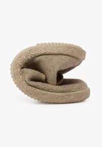 Zapato de estilo slip-on en color tawny con textura trenzada, con forma redondeada, forro suave y suela gruesa similar al yute con acentos mínimos.
