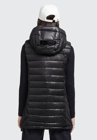 Czarna puchowa kamizelka z kapturem, z błyszczącymi pikowanymi panelami i logo na plecach. Materiał wydaje się gładki i lekki.