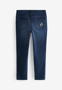 Sötét farmernadrág, slim fit fazonban, két hátsó zsebbel és virágmintás hímzéssel a jobb zsebén.