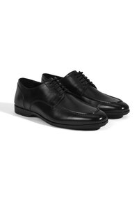 Zwarte leren schoenen met een gladde afwerking, ronde neus, smalle veters en subtiele stikdetails langs de bovenkant en zijkant.