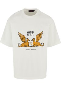 Hvitt bomull T-skjorte med et grafisk design av to bevingede griffiner med oransje detaljer og svart tekst som leser "BER N.Y.C." og "Prohibited, Spring 24."