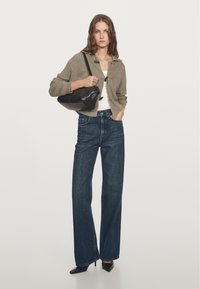 Oliwkowo-zielony prążkowany kardigan, biała koszula i jeansy o szerokich nogawkach i wysokim stanie w ciemnym odcieniu. Czarna torebka na ramię i czarne szpilki z ostrym noskiem.