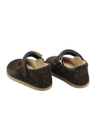 Zapatos Mary Jane de ante marrón con puntera redondeada, tira elástica y suelas de goma. Presentan detalles recortados en los laterales y superficie texturizada.